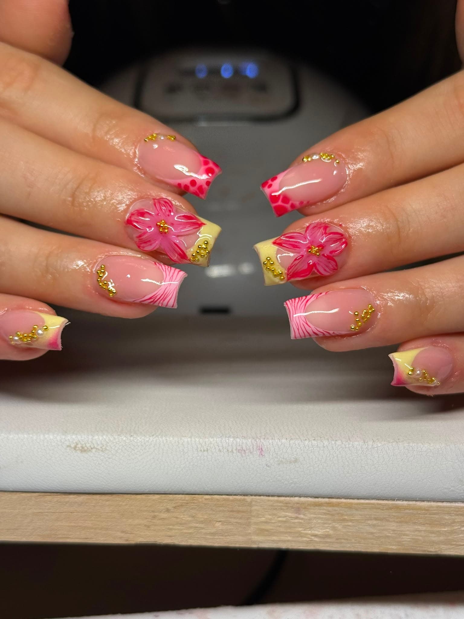 Tropische nail art met roze en gele tips, handgemaakte 3D-bloemen en gouden kraaltjes